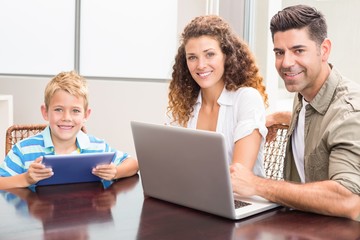 Fototapeta na wymiar Happy parents sitting with son using tablet and laptop
