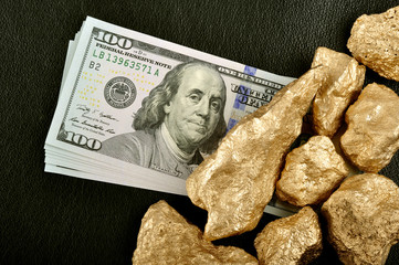 Gold nuggets and U.S. dollars on a black background leather. Clo © Andrii Medvediev