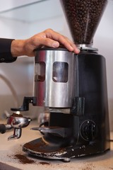 Barista using coffee grinder to grind beans