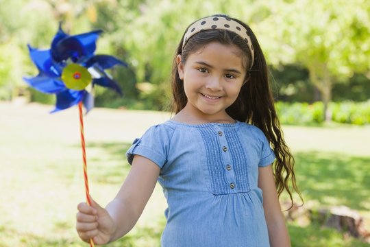 Cute little girl holding pinwheel at park