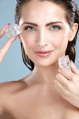 Beautiful woman applying ice cube treatment on face