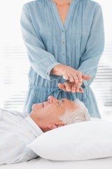 Obraz na płótnie Canvas Therapist performing Reiki over forehead of man