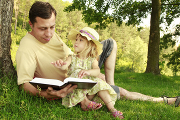 young father with his little daughter reads the Bible
