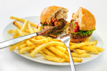 Halved hamburger with fries on dish