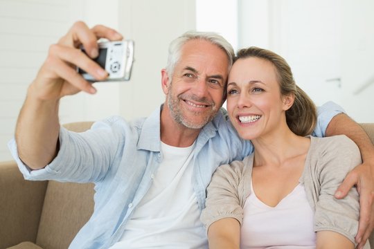 Happy couple taking a selfie together on the couch