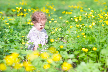 Cute baby girl playing with yellow flowers