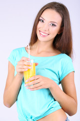 Beautiful girl with fresh juice on grey background