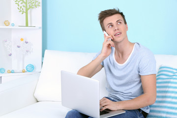 Guy talking of phone with laptop on blue background