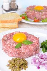 Delicious steak tartare with yolk on plate on table close-up
