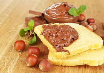 Bread with sweet chocolate hazelnut spread on wooden background