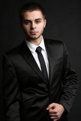 Handsome young man in suit on dark background