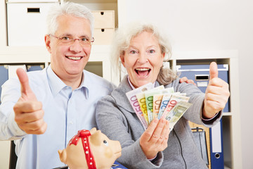 Senioren mit Geld halten Daumen hoch