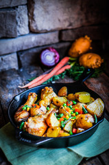 Oven baked chicken with potatoes and vegetables on wooden backgr