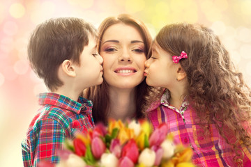 Happy mother kissed by her daughter and son