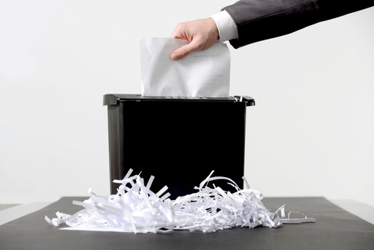 Hand of businessman putting a document in paper shredder