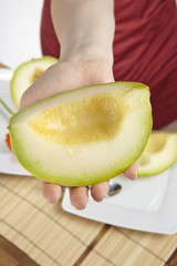 Junge Frau bietet ein Viertel einer Galiamelone an