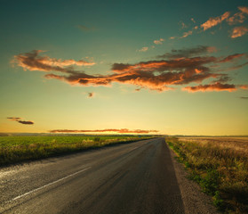 Naklejka na ściany i meble Lonely road leading to the horizon at sunset sky background