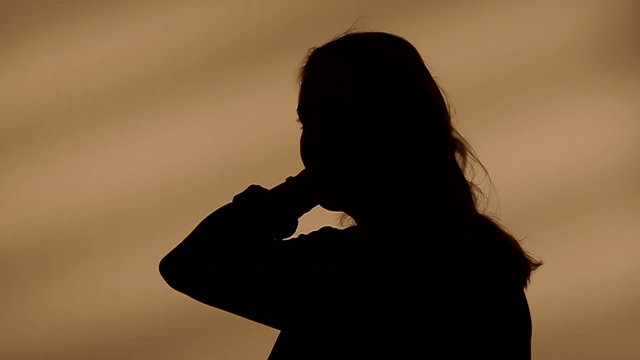 Female silhouette goes with her hands through her hair
