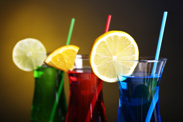 Glasses of cocktails on table on dark yellow background