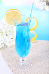 Glass of cocktail on table on light blue background