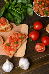 Delicious bruschetta with tomatoes on cutting board close-up