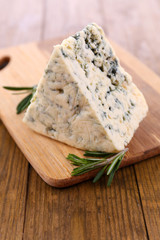 Tasty blue cheese with rosemary, on wooden table