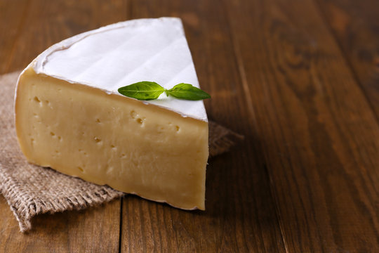 Tasty Camembert cheese with basil, on wooden table