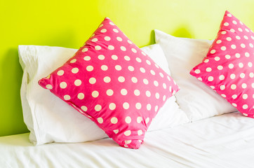 Colorful polka pillow on white bed
