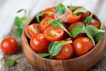 Wooden bowl with fresh cherry tomatoes and corn salad, close-up