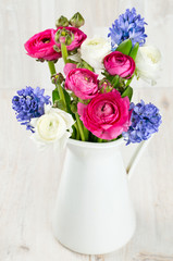 ranunculus and hyacinth flowers in a pitcher