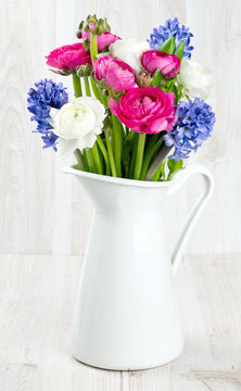 ranunculus and hyacinth flowers in a pitcher