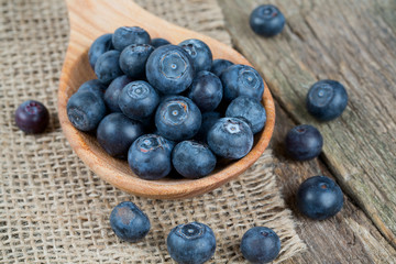fresh blueberries in a wooden spoon over wooden table