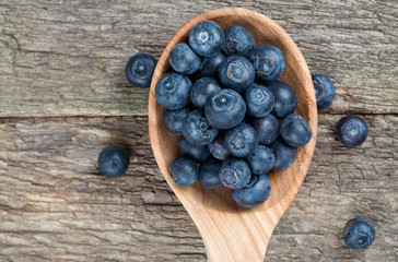 fresh blueberries in a wooden spoon over wooden table