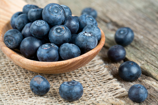 fresh blueberries in a wooden spoon over wooden table