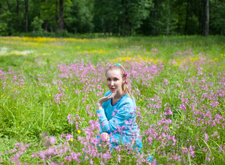 The happy young woman in the field of wild flowers..