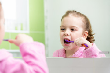 child girl brushing teeth in bathroom