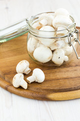 Fresh mushrooms in a glass jar on a wooden surface