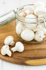 Fresh mushrooms in a glass jar on a wooden surface