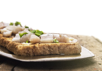 toast with salted herring and onion on metal tray, isolated