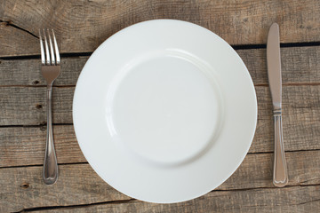 Empty plate with fork and knife on the vintage wooden table