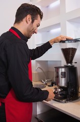 Happy barista grinding coffee beans