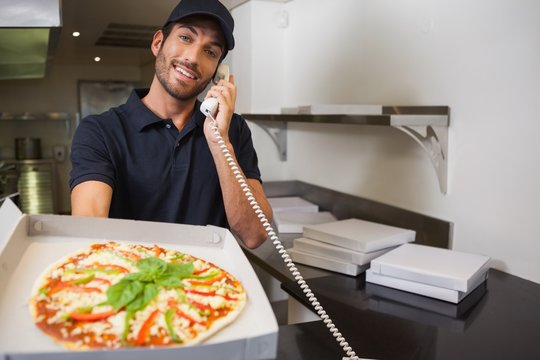 Smiling Pizza Delivery Man Taking An Order Over The Phone