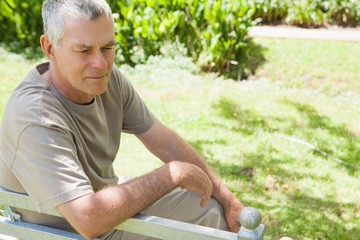 Thoughtful mature man sitting on park bench