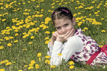 Fototapeta premium Girl in the flowering meadow looking at camera