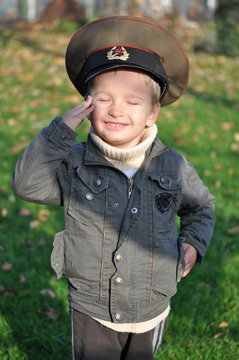 Boy salutes in military cap