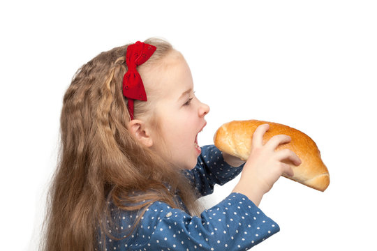 Little hungry girl biting a bun isolated on white background