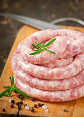 Fresh raw sausage on the old wooden background