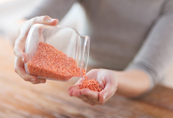 close up of female emptying jar with red lentils