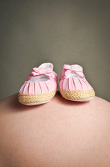 Little baby shoes on a pregnant stomach