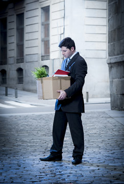 frustrated business man on street fired carrying cardboard box